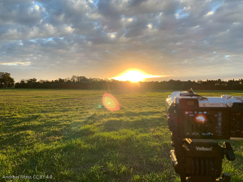 sun in the background. A digital camera in the foreground, making a picture of the solar eclipse