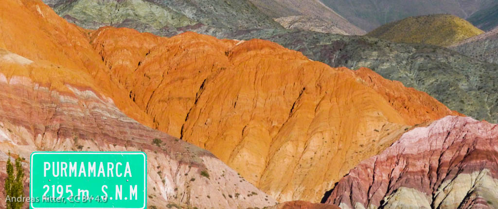 colorful mountains. A green traffic sign saying Purmamarca in the foreground